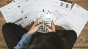 Top view man sitting on the floor stressed and confused by calculating expenses from bills
